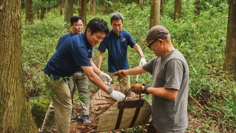 カートピア 森の中で焚き火に使う小枝を集める寒川さん、藤井さん、中野さん、齋藤さん | SUBARU